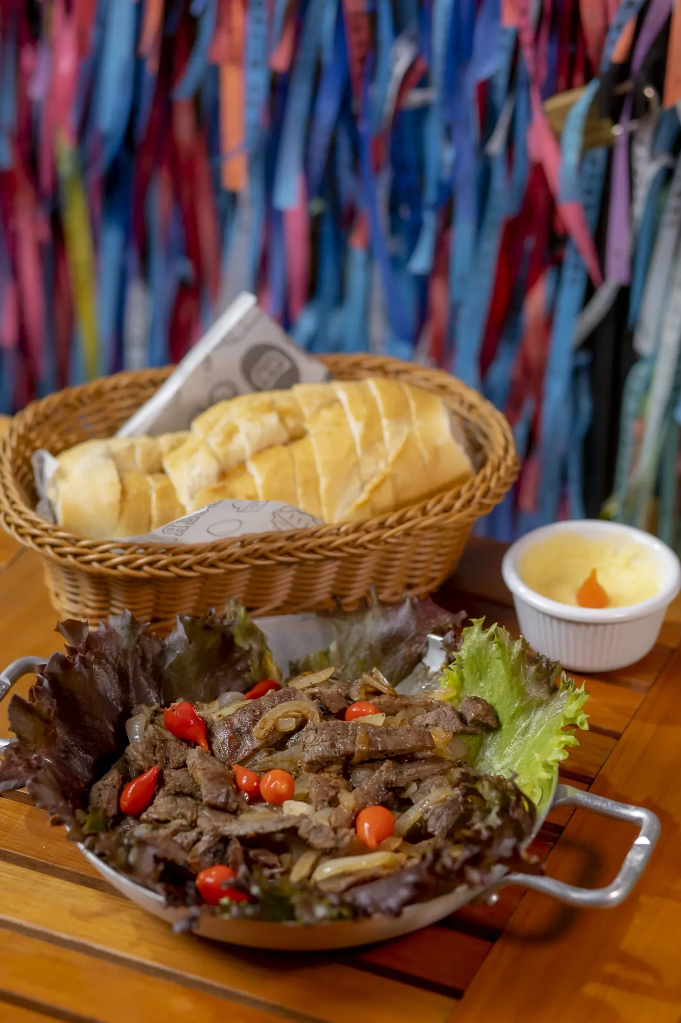 Porção de carne acebolada com pão sobre mesa de madeira